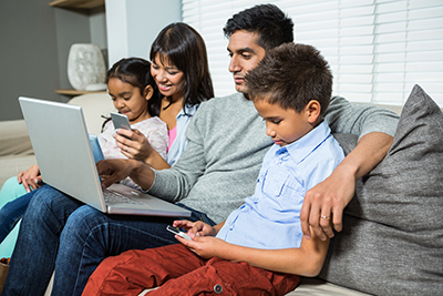 family-looking-at-screens-while-sitting-on-couch