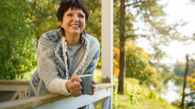 Happy woman leaning on deck with coffee