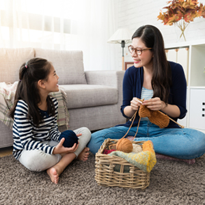 Mom and daughter sitting and knitting with yarn