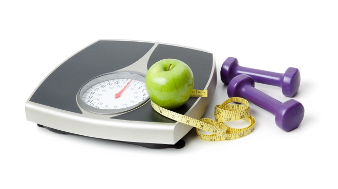 Scale, hand weights, measuring tape, green apple