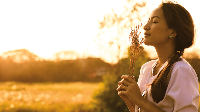 Woman smelling flowers with eyes closed