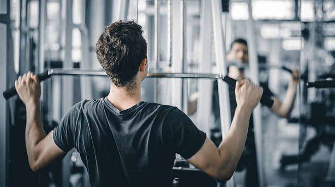 Man using a lat bar in gym