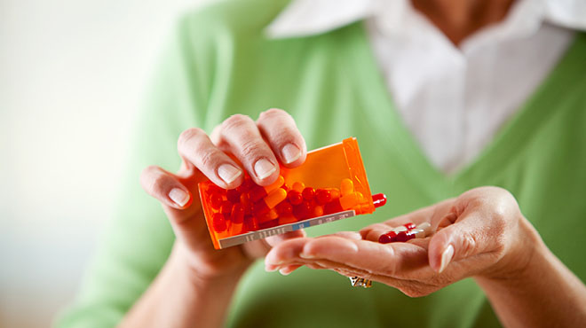 Prescription bottle emptying capsules into hand