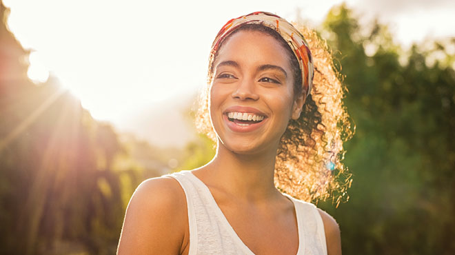 Young woman smiling with sun shining in the background