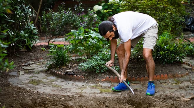 Bending over shoveling dirt