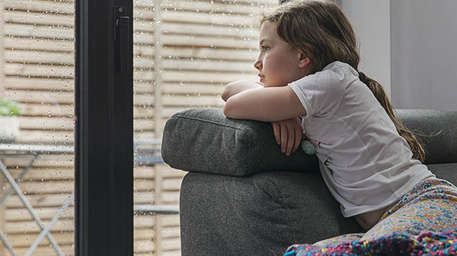 Child with crossed arms resting on a sofa