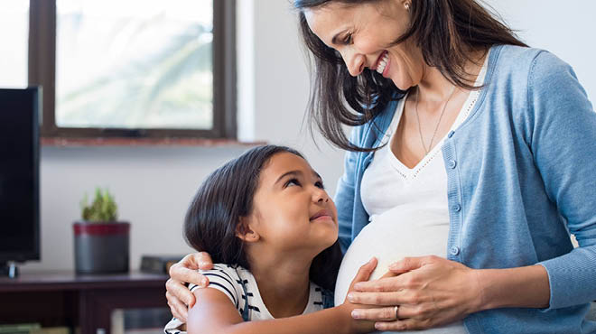 Daughter touching mother's pregnant belly