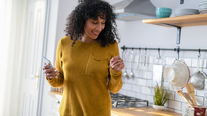 Holding cellphone in hand in kitchen