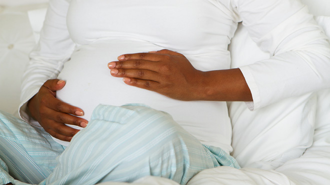 Seated pregnant woman with hands cupping belly