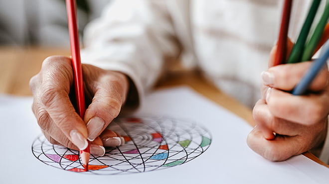 Person coloring in an adult coloring book with colorful pencil