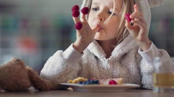 Child with berries on fingertips