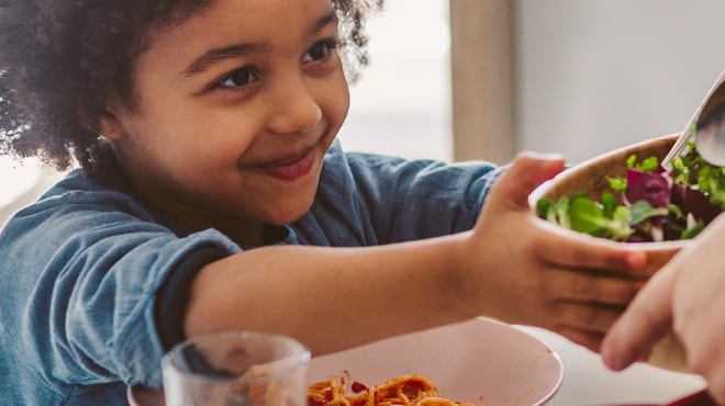 Handing bowl of salad to child