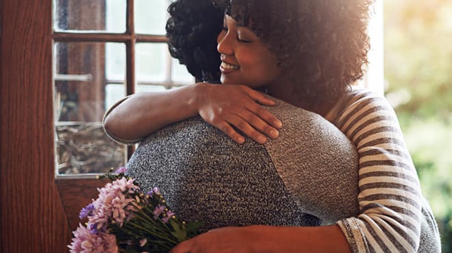 Hugging couple holding flowers