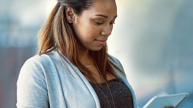 Looking down at tablet, wearing a grey sweater