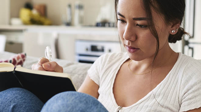 Sitting on sofa writing in journal