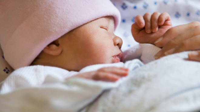 Sleeping baby wearing pink cap