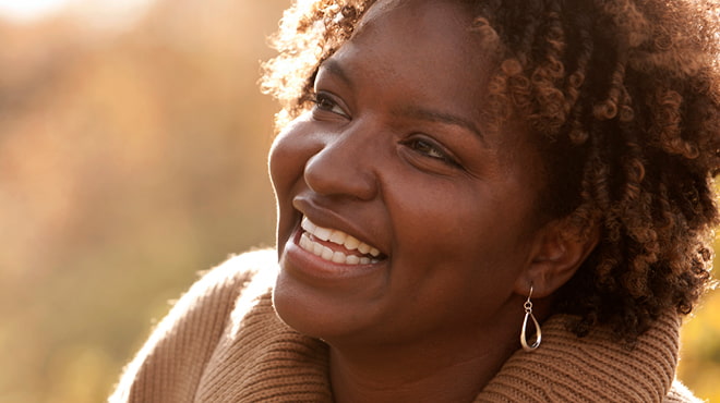 Smiling person wearing a tan sweater