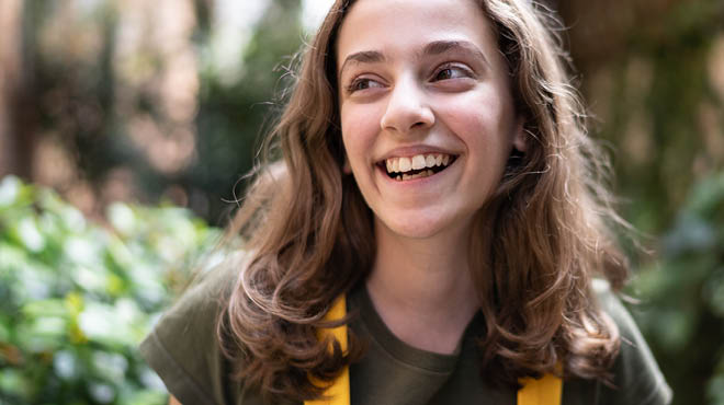 Teen smiling, wearing backpack with yellow straps
