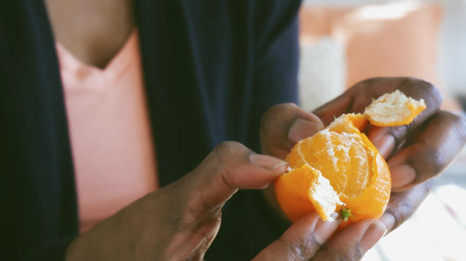 Fingers peeling clementine