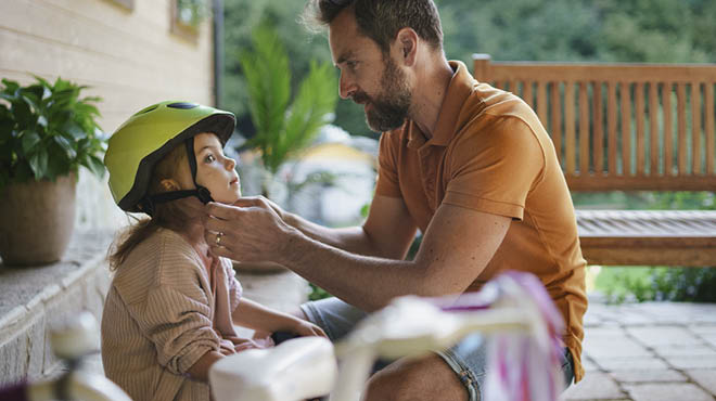 Parent clipping bike helmet on child