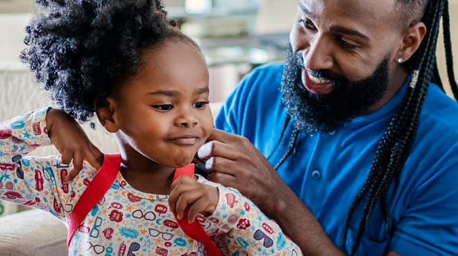 Parent helping child with backpack