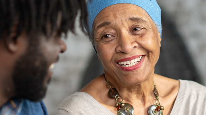 Person wearing cancer cap smiling at another person