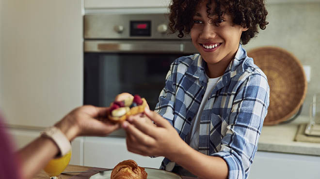 child in kitchen handing food to another