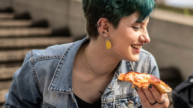 Holding pizza slice outdoors